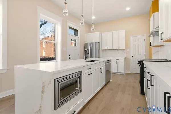 a large kitchen with kitchen island a sink a stove a refrigerator and a dining table with wooden floor