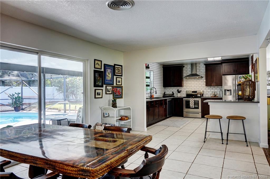 905 Southeast Flamingo Avenue Stuart, FL 34996 - Photo 12 of 36 a kitchen with a table chairs and a refrigerator