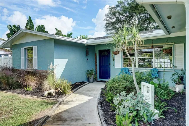 a view of a yard with plants and a table and chair