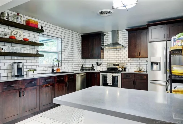 a large kitchen with stainless steel appliances granite countertop a sink dishwasher stove and refrigerator with wooden cabinets