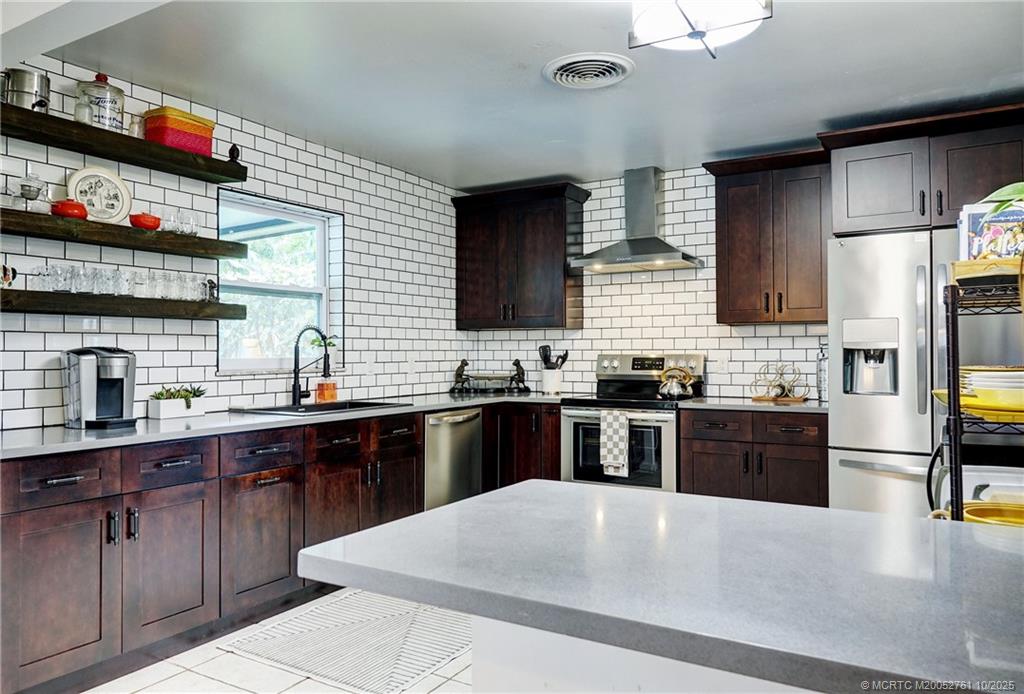 905 Southeast Flamingo Avenue Stuart, FL 34996 - Photo 4 of 36 a large kitchen with stainless steel appliances granite countertop a sink dishwasher stove and refrigerator with wooden cabinets
