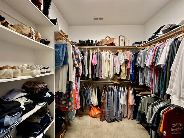 a view of walk in closet with clothes and shoes
