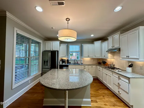a kitchen with sink refrigerator dining table and chairs