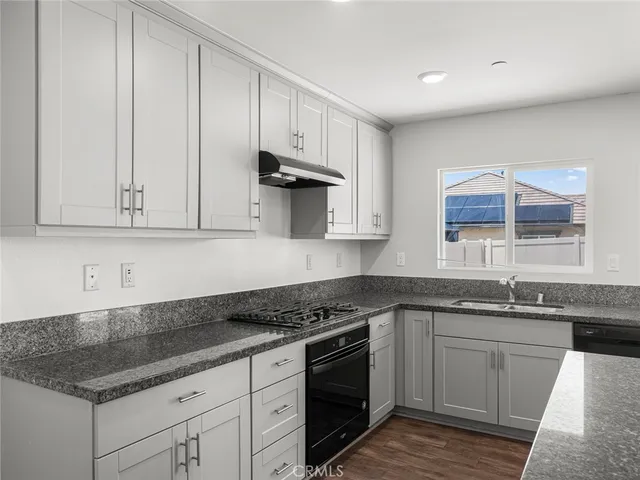 a kitchen with granite countertop white cabinets and a stove