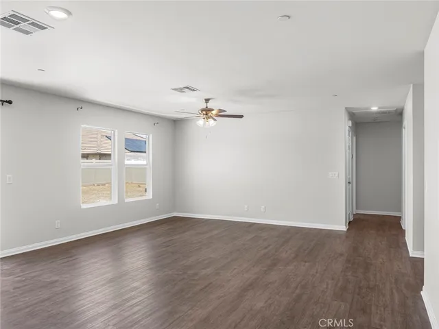 an empty room with wooden floor chandelier fan and windows
