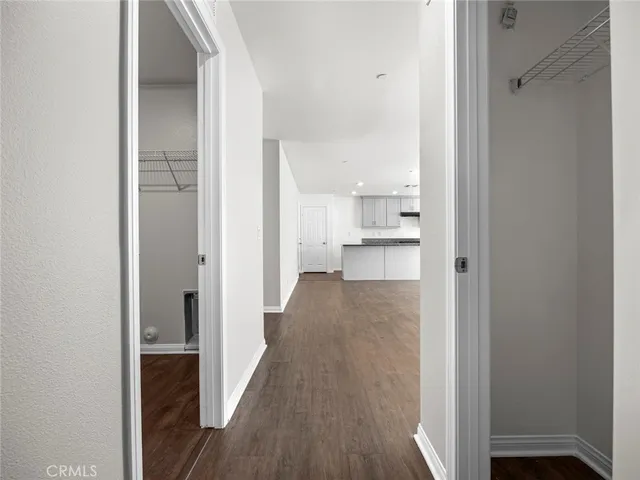 a view of a hallway with wooden floor and a bathroom