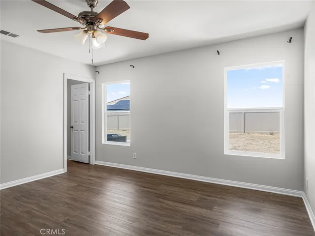 an empty room with wooden floor chandelier fan and windows