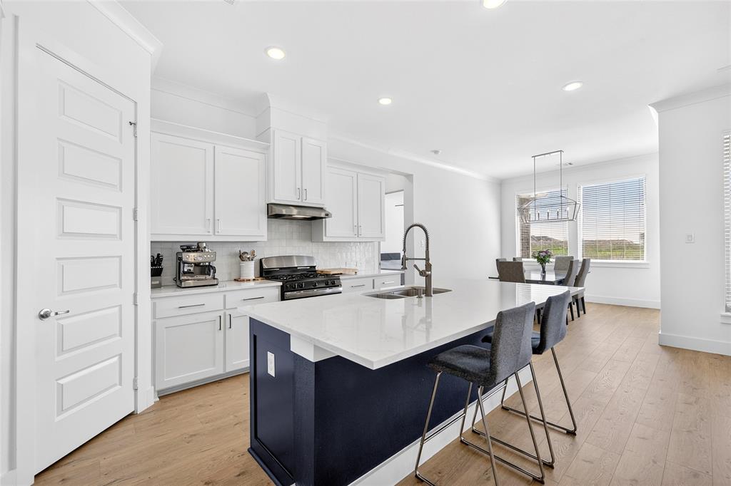 209 Basalt Lane Azle, TX 76020 - Photo 19 of 39 a kitchen with a sink a stove a refrigerator and white cabinets with wooden floor