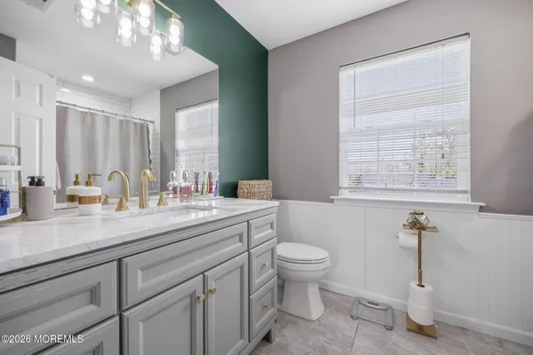 a bathroom with a granite countertop sink a toilet and a mirror