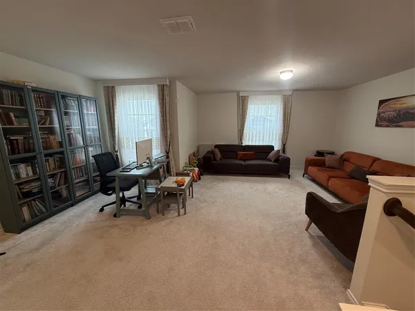 a living room with furniture a bookshelf and a window