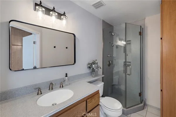 a bathroom with a granite countertop sink toilet a mirror and shower