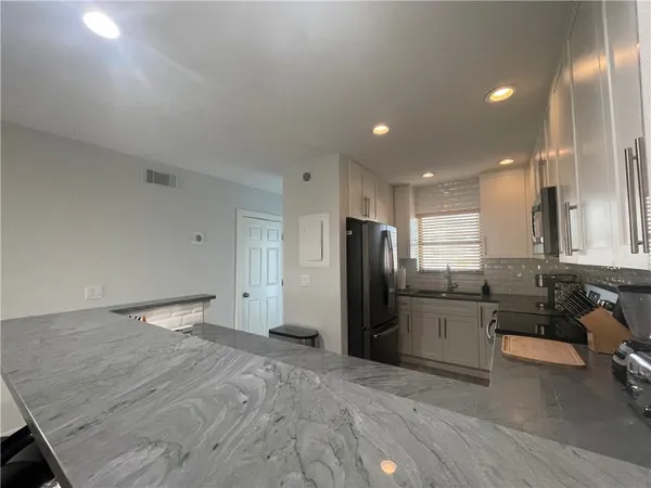 a large kitchen with stainless steel appliances kitchen island granite countertop a refrigerator and a sink