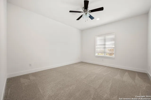 en empty room with ceiling fan and window