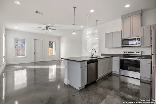 a kitchen with stainless steel appliances granite countertop a stove a sink and a microwave