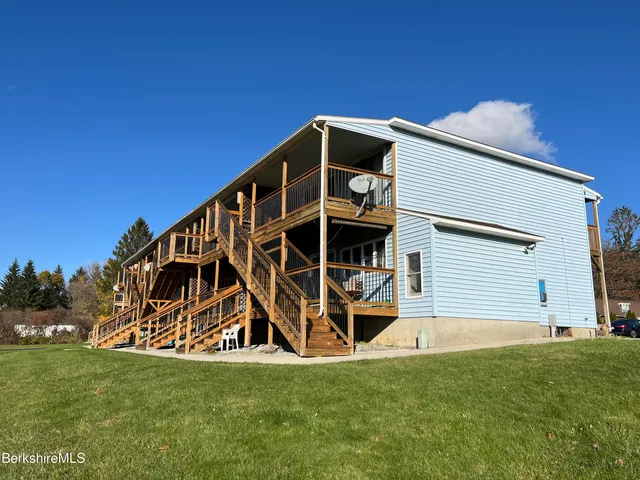 a view of wooden house with grass and stairs