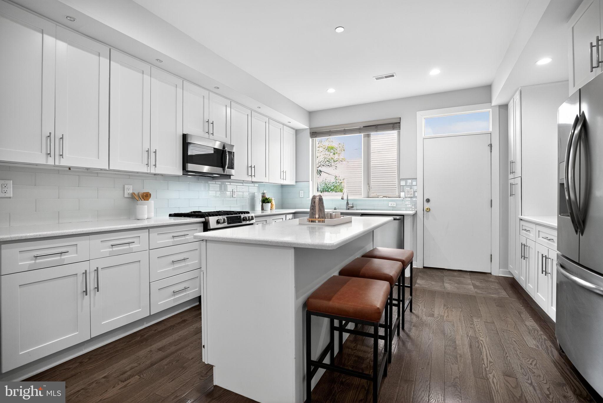1711 South 20th Street Philadelphia, PA 19145 - Photo 8 of 36 a kitchen with white cabinets and stainless steel appliances