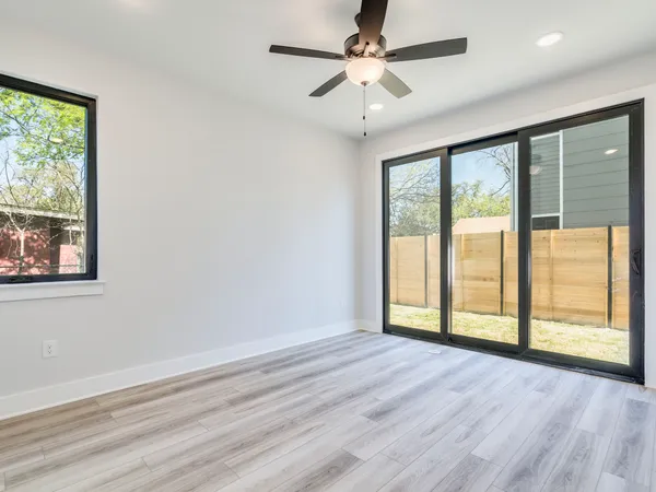 a view of an empty room with a window and wooden floor