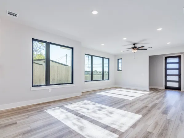 a view of an empty room with a window and wooden floor