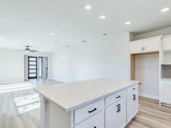 a large white kitchen with kitchen island a sink wooden floor and stainless steel appliances