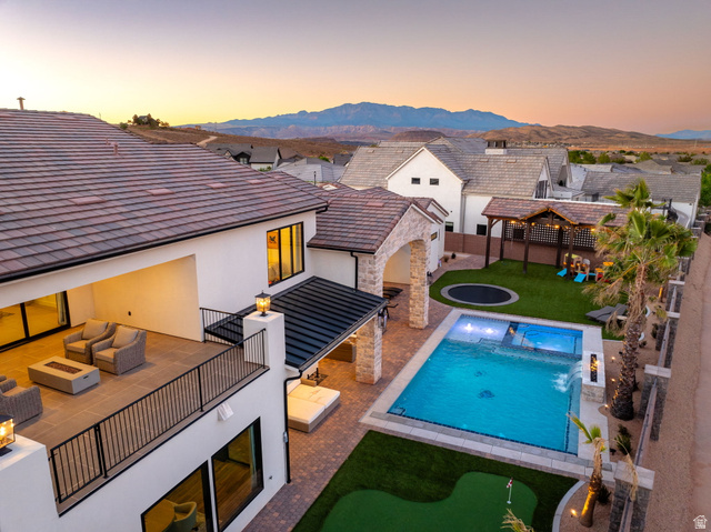 4871 South Homestead Way Washington, UT 84780 - Photo 140 of 151 View of pool with patio surround, an outdoor living space with a fire pit, a putting green, a fenced backyard, and a mountain view