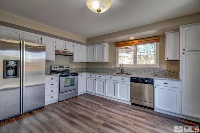 a kitchen with granite countertop wooden floors stainless steel appliances a sink and a window