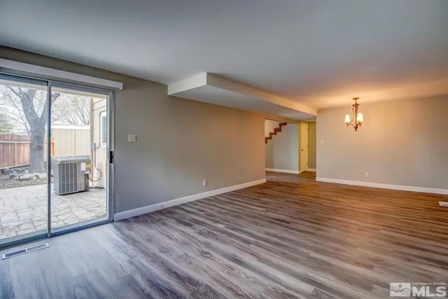 a view of an empty room with glass door and wooden floor