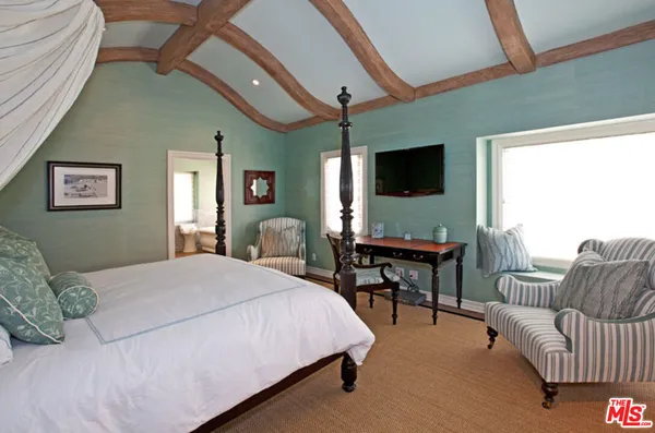 a bedroom with a bed a couch and a flat screen tv