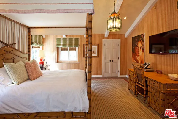 a bedroom with a bed and a flat tv screen on dresser