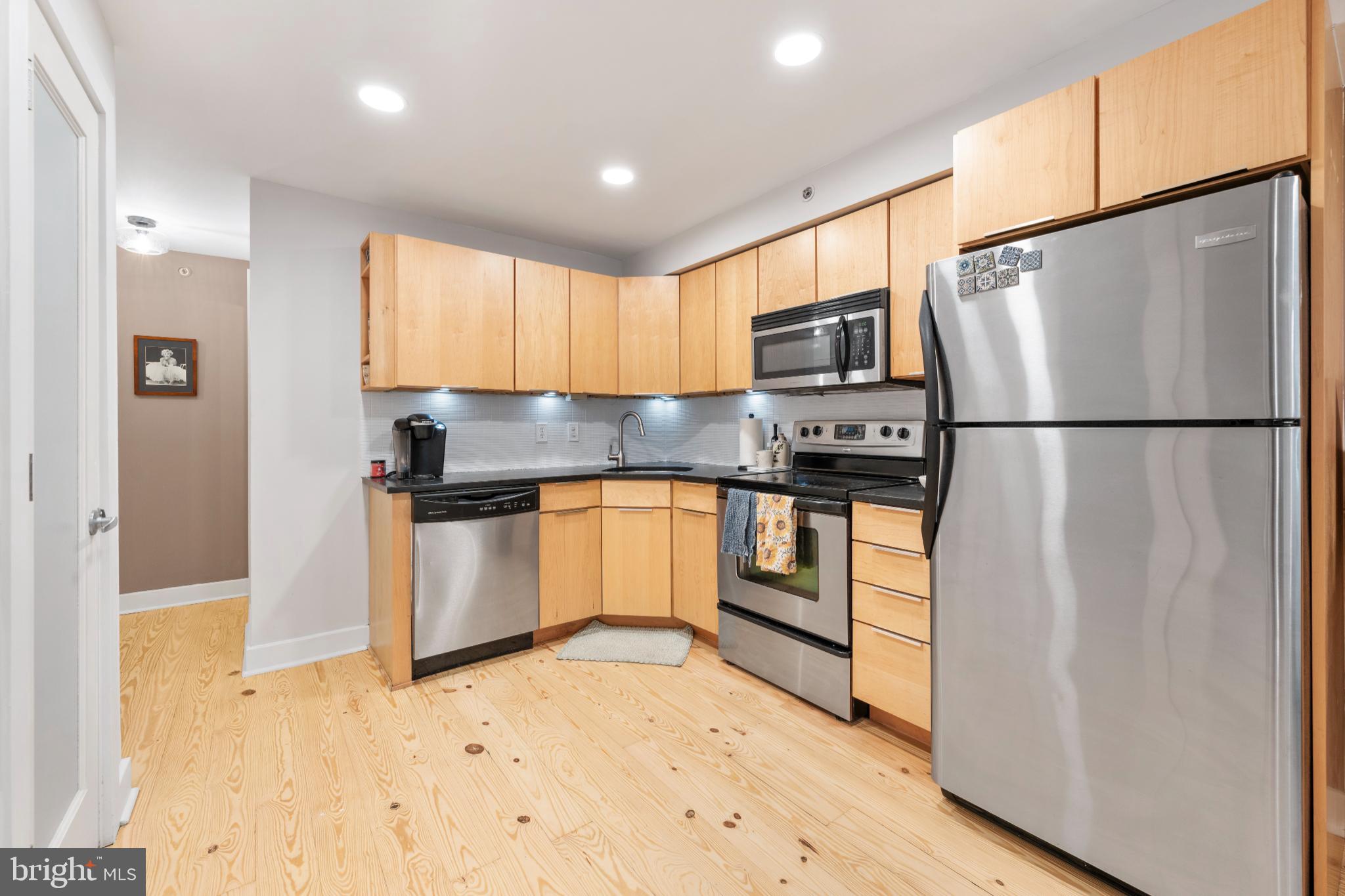 2123 Christian Street, Unit A Philadelphia, PA 19146 - Photo 5 of 15 a kitchen with granite countertop a refrigerator a sink and white cabinets