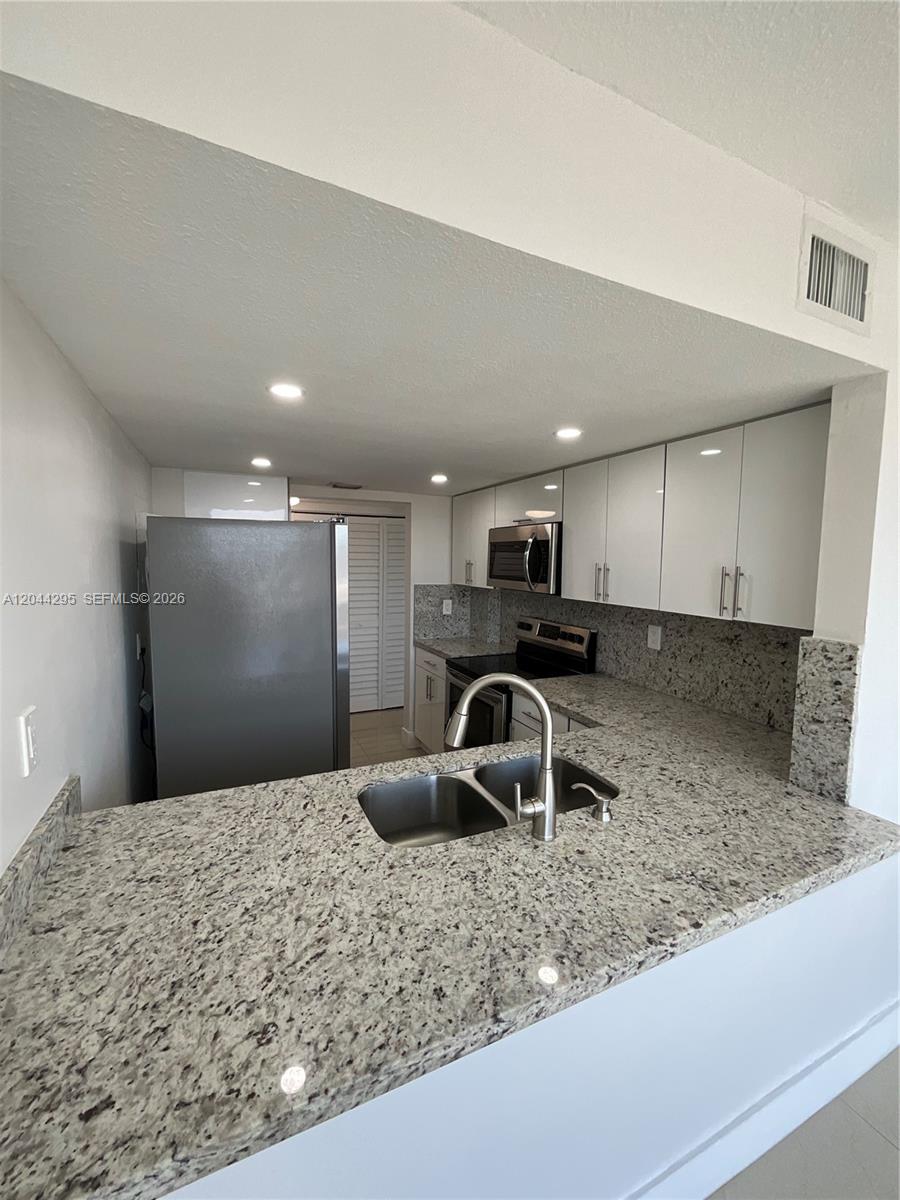 9441 Southwest 4th Street, Unit 214 Miami, FL 33174 - Photo 1 of 22 a view of a kitchen with kitchen island a sink wooden floor and a counter top space