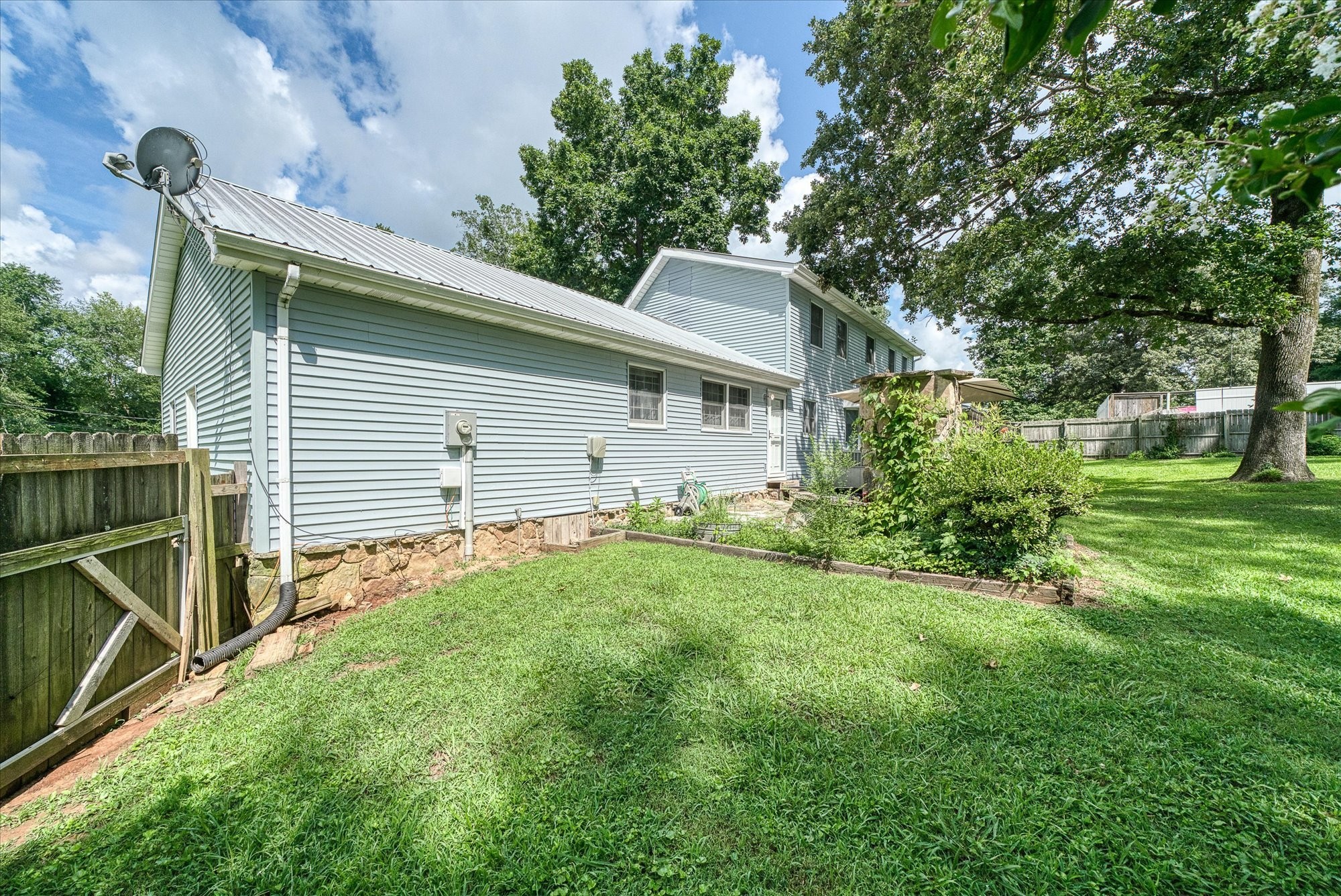 221 Magnolia Road Sparta, TN 38583 - Photo 22 of 36 a backyard of a house with plants and large tree
