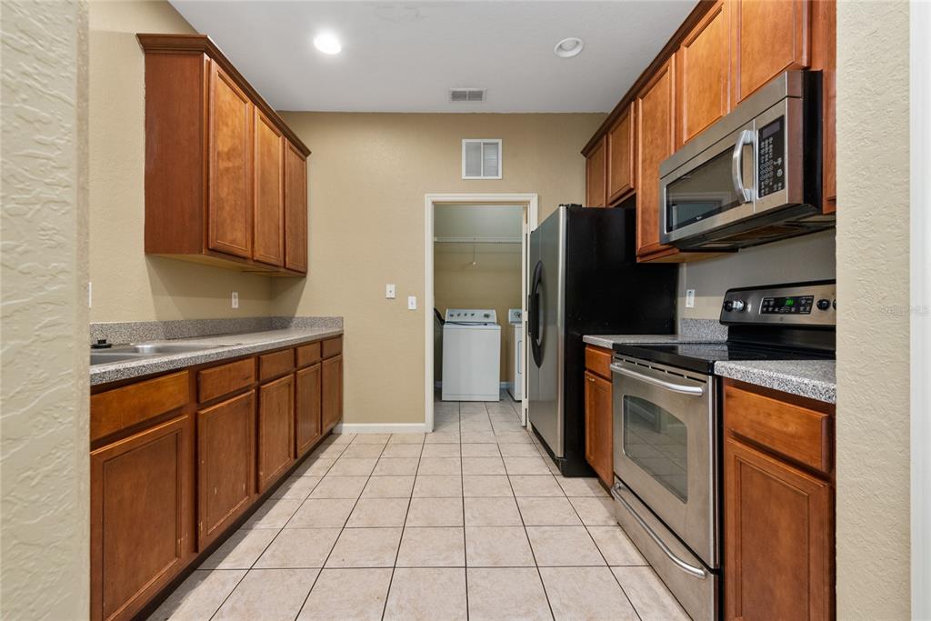 3051 Greystone Loop, Unit 201 Kissimmee, FL 34741 - Photo 7 of 20 a kitchen with stainless steel appliances granite countertop a refrigerator a stove top oven and sink