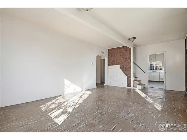 a view of an empty room with wooden floor and window