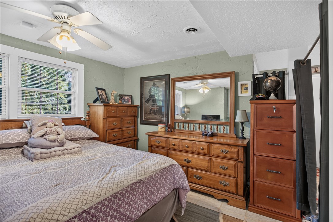 104 Laurel Lane Seneca, SC 29678 - Photo 23 of 36 Natural light filters into this inviting bedroom, featuring warm wooden furnishings and textured wall accents.
