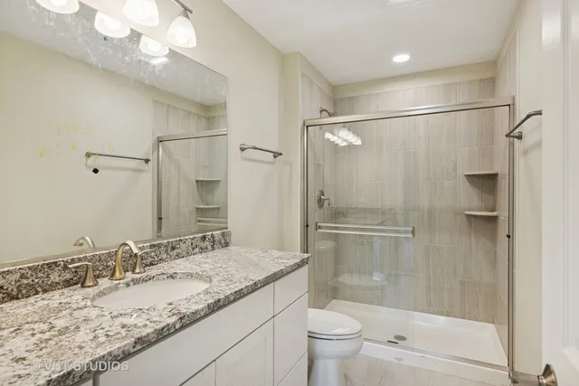 a bathroom with a granite countertop sink toilet and shower
