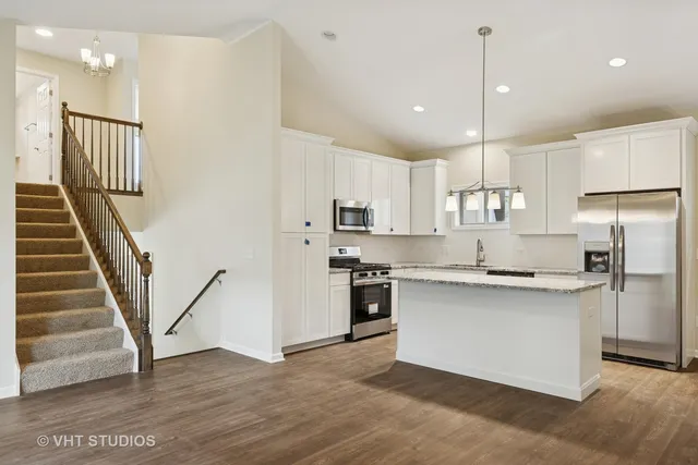 a kitchen with stainless steel appliances granite countertop a refrigerator a sink and a stove