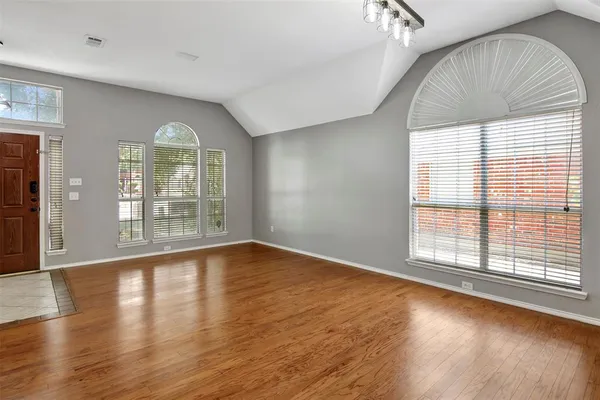 an empty room with wooden floor and windows