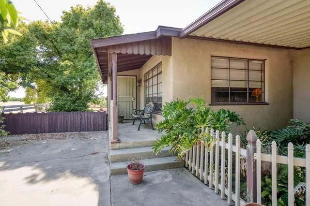 a view of a patio with a dining table and chairs under an umbrella with a barbeque