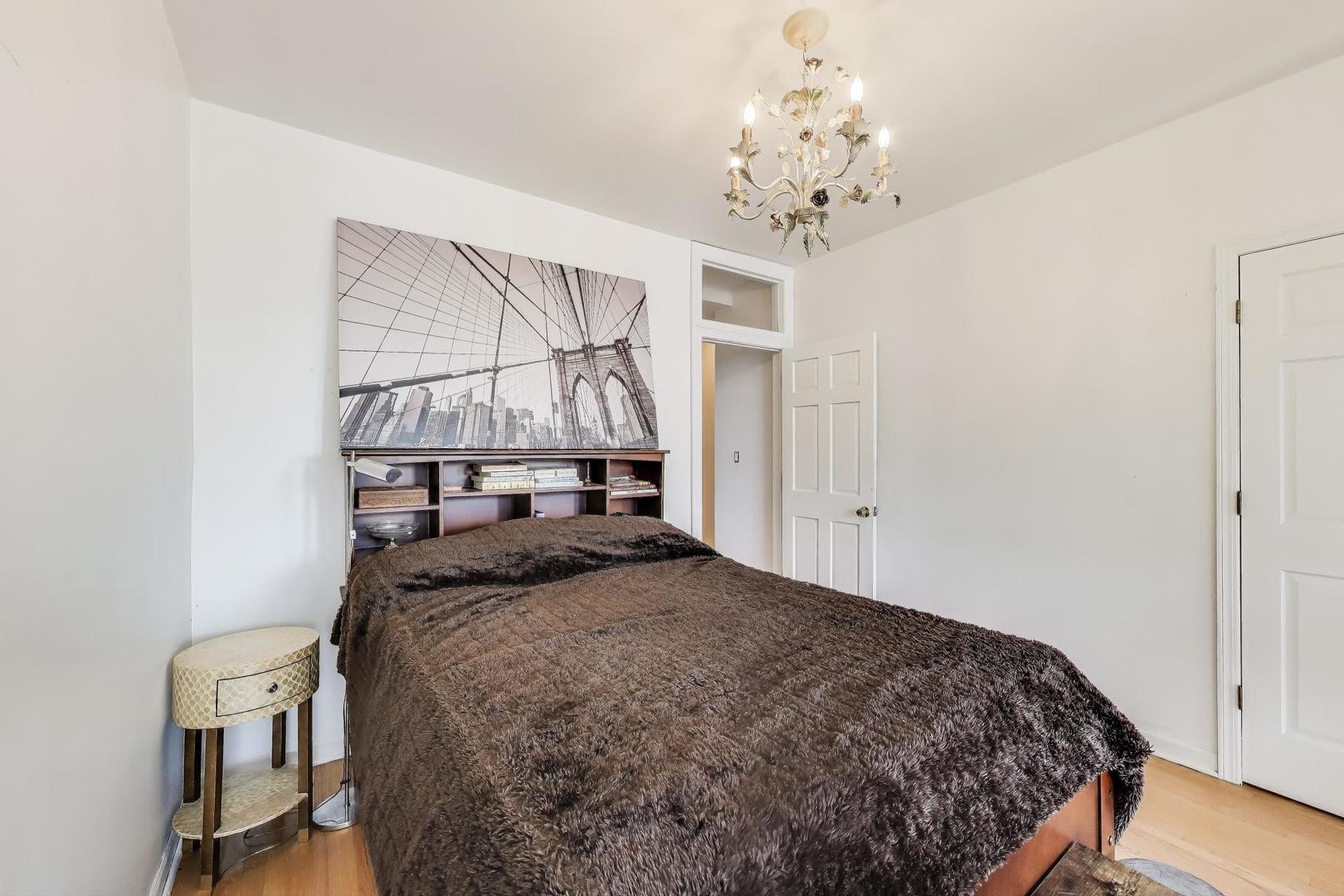 4553 South Ellis Avenue Chicago, IL 60653 - Photo 29 of 62 a bedroom with a bed and a chandelier