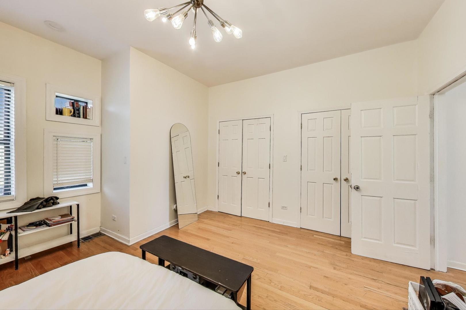4553 South Ellis Avenue Chicago, IL 60653 - Photo 42 of 62 a spacious bedroom with a bed and a chandelier