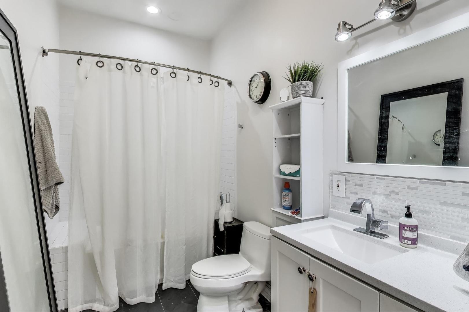 4553 South Ellis Avenue Chicago, IL 60653 - Photo 43 of 62 a bathroom with a sink a toilet and shower curtain