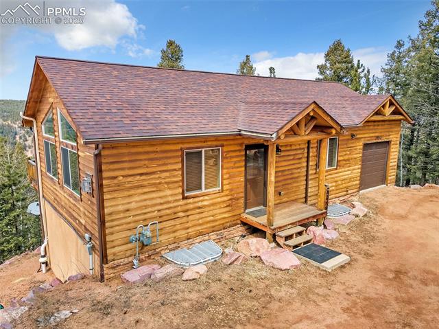 1055 Timber Ridge Road Divide, CO 80814 - Photo 38 of 47 View of front of house featuring faux log siding, a shingled roof, and a garage