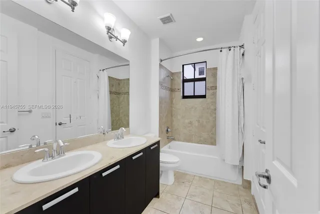 a bathroom with a double vanity sink a mirror a bathtub and shower