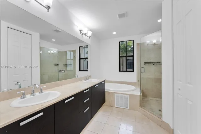 a spacious bathroom with a double vanity sink a large mirror and a bathtub
