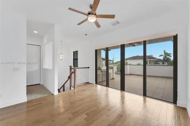 a view of a hallway with wooden floor and a chandelier fan