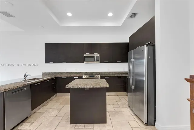 a kitchen with a sink a counter top space cabinets and stainless steel appliances
