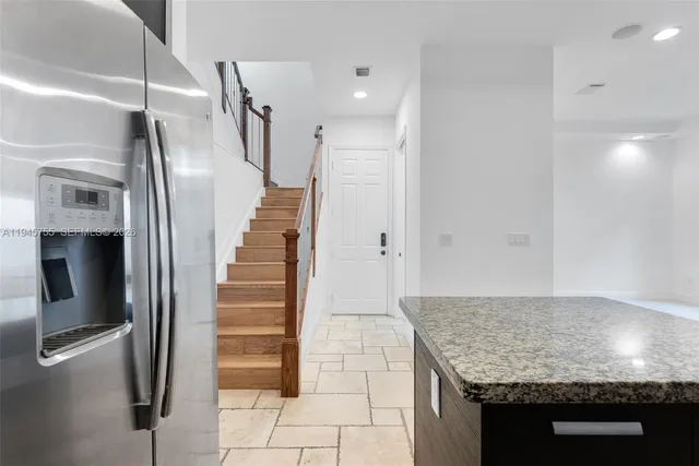 a kitchen with granite countertop a refrigerator and a sink