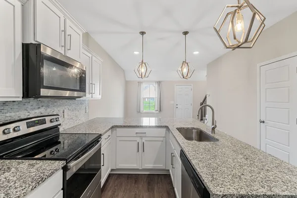 a kitchen with granite countertop a sink stainless steel appliances and cabinets