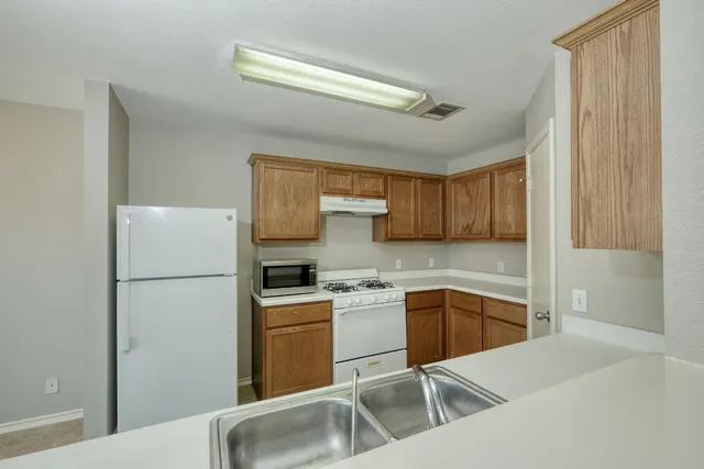 a kitchen with a sink a stove a refrigerator and cabinets