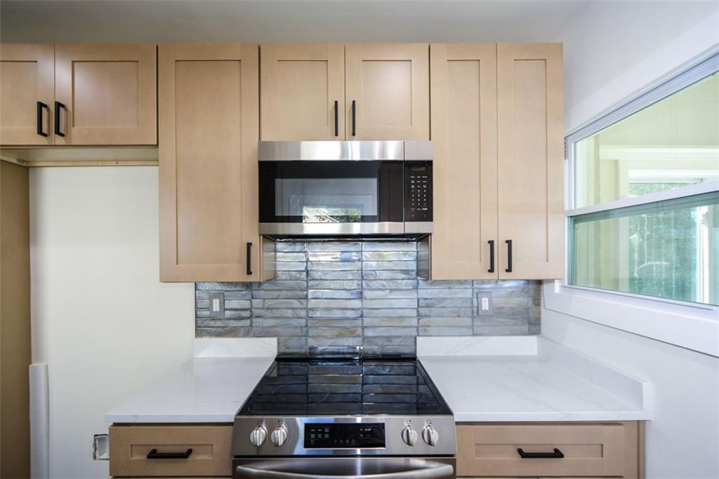 1275 Westridge Road Southwest Atlanta, GA 30311 - Photo 12 of 38 a kitchen with stainless steel appliances a stove a microwave and cabinets